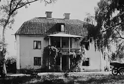 Two-storey, light-coloured building with a gambrel roof