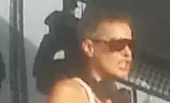 Person with cropped hair wearing dark sunglasses and a sleeveless top.