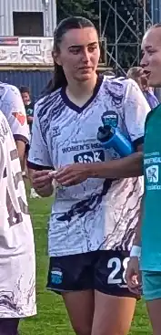 Player on the pitch after a match with a water bottle under her arm