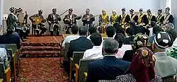 People sitting in rows of chairs, listening to Shashmaqom being played