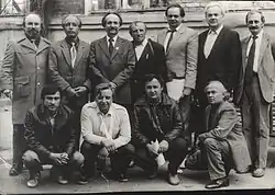 A photograph of eleven men in suits standing or squatting