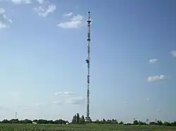 Tall communications tower on flat ground, with guy wires