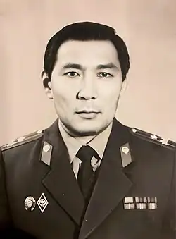 A Central Asian man in a military uniform looks at the camera