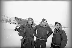 The Soviet naval fighter pilot Boris Safonov (left), along with the No.&nbsp;151 Wing RAF airmen A.&nbsp;G.&nbsp;'Tony' Miller (center) and C.&nbsp;'Wag' Haw (right), and a&nbsp;Hawker Hurricane Mk&nbsp;IIB fighter (background) that would later be donated to the Northern Fleet Air Force after Operation Benedict; 1941