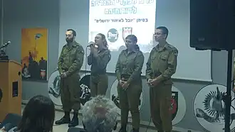 Four soldiers standing in front of a projector screen