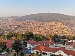Panorama photograph showing houses in foreground, with Mount Kigali in the background