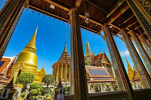 View from the ubosot, framed by gilded columns, overlooking the temple complex.
