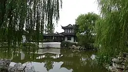 A pond and garden surrounding a traditional Chinese residence