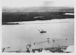 Anti-submarine boom (net) at Fort Lytton during the Second World War. Two moving boom gates were operated by winches located at the fort and on the permanently anchored ship.[gallery 12]