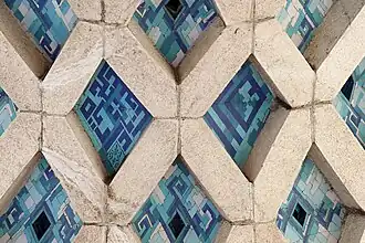 Detail of the tile work underneath the arch with texts including the name of architect and the construction date