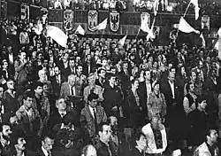 Several individuals gathered at a conference, some of them waving Ukrainian flags or wearing vyshyvanka