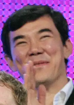 Koyanbayev seen smiling and applauding, he wears a suit