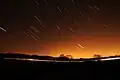 Short streaks of light on a dark sky, showing star trails that were photographed with a long exposure.