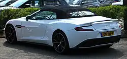 A white convertible with its rooftop closed. It has a United Kingdom licence plate and there are other cars parked in the background