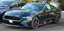 Front three-quarters view of a very dark green coupe
