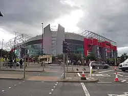 View from a roadside of a mainly grey football stadium with red highlights