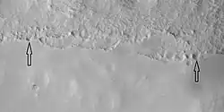 Close view of mantle, as seen by HiRISE under HiWish program Arrows show craters along edge which highlight the thickness of mantle. Mantle may be used as a water source by future colonists. Location is Ismenius Lacus quadrangle.