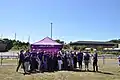 Images shows staff and volunteers celebrating outside a marquee.