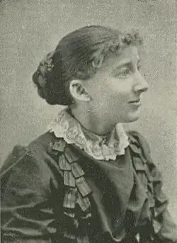 19th-century B&W portrait photo of a woman with her hair in an up-do, wearing a dark, fitted blouse.