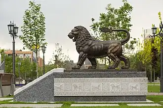 A bronze lion statue is installed at the entrance of the park