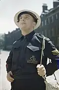 An ARP Warden for the London neighbourhood of Holborn surveys bomb damage in dark blue battledress.