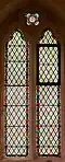 A north window in the church. This example was damaged by vandalism; minor differences can be noticed in the left panes that were replaced