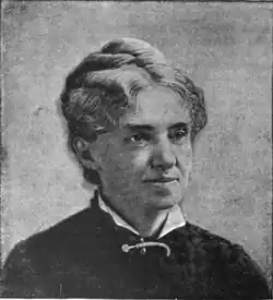 B&W portrait photo of a middle-aged woman wearing a dark, high-collared blouse with her hair in an up-do.