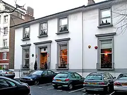 A colour image of the façade of a brick building that is painted white