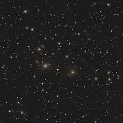 A field of stars and galaxies. Most of the galaxies are elliptical, yellow blobs among more circular stars.