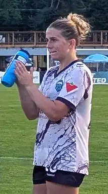 Left profile of player in uniform on the pitch holding a water bottle