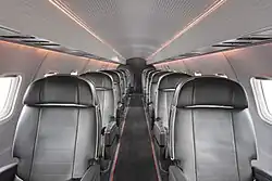 Interior of the Aero ERJ-135 jet featuring black leather seats, a 1-1 layout, and ambient lighting.