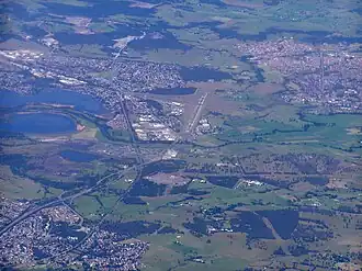 An aerial view of the area looking south, with Yallah, bottom left; Albion Park Rail, top left; Albion Park, top right; and Lake Illawarra, centre-left.