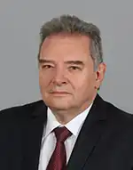 Portrait photograph of Paunov, 68, wearing a suit and a red tie.