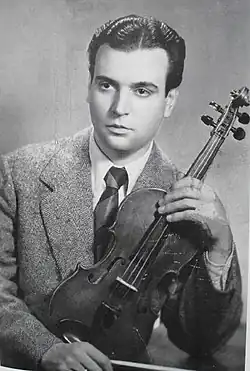 black-and-white photo of Alfredo Gobbi holding a violin, left elbow propped on a table, looking right of camera