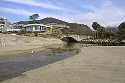 A creek flows out of a gap through a coastal mountain range and flows onto the beach.