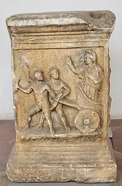 A photo of a marble altar containing a carving which depicts the myth of Kleobis and Biton.