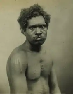 Portrait photograph of an Aboriginal man with a scarred torso