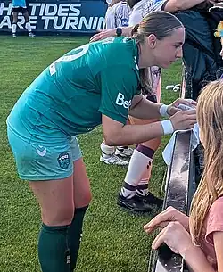 Left profile of player in uniform signing autographs after match