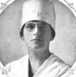A white woman with dark hair, wearing a chef's hat and glasses