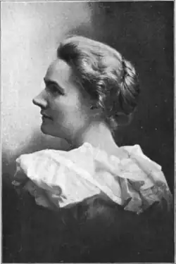 20th-century B&W portrait photo of a woman with her hair in an up-do, wearing a pale, fitted blouse.