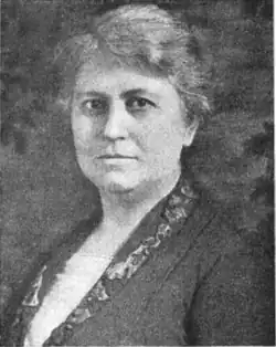 20th-century B&W portrait photograph of a woman with short hair wearing a white blouse and dark jacket.