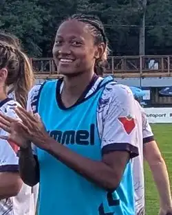 Player in uniform on the pitch smiling and clapping