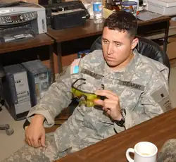 Photograph from above of a uniformed Aguilar inspecting a pair of glasses