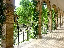 2011 photograph of a lycée corridor, showing arcades, greenery, and the playground.