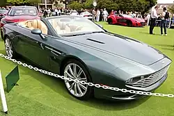A front three-quarters view of a dark green convertible with its roof opened at a car show