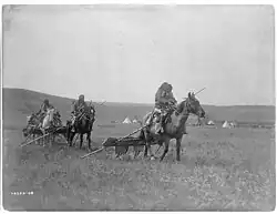 Gros Ventre (Atsina) American Indians moving camps with travois for transporting skin lodges and belongings.