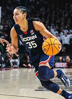 Shot of Azzi Fudd in the middle of a game, dribbling a basketball.