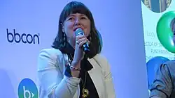 Headshot of Jones speaking into a microphone against a blue background