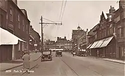 Photo Postcard of Park Street in the 20th Century, with people walking, people on bicycles, old cars, and a delivery lorry and churns