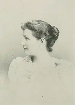 19th-century B&W portrait photo of a woman with her hair in an up-do, wearing a dark, fitted blouse.